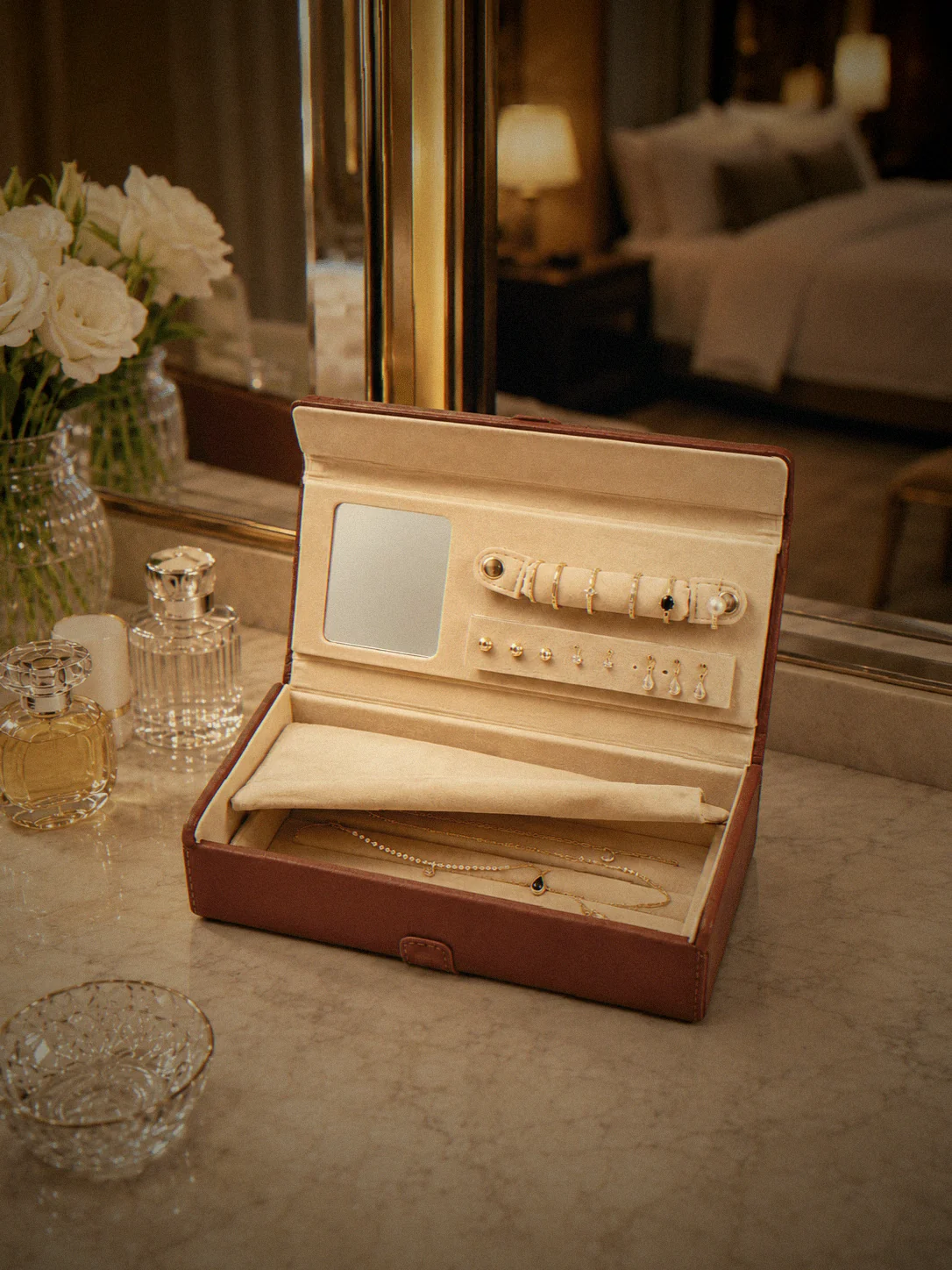 The jewelry box open on a marble vanity, rings on the roll and necklaces in the tray